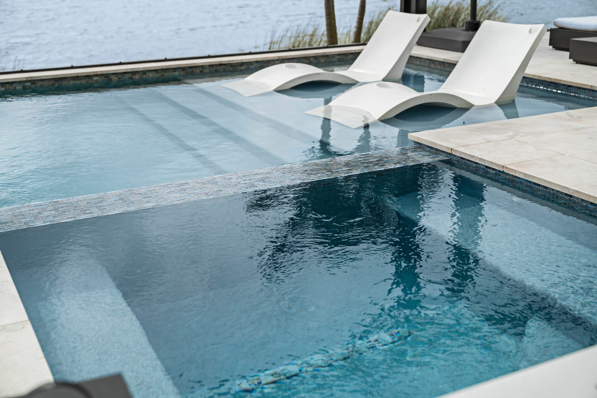 Beach entry zero-edge gradual pool entry with natural stone surrounding
