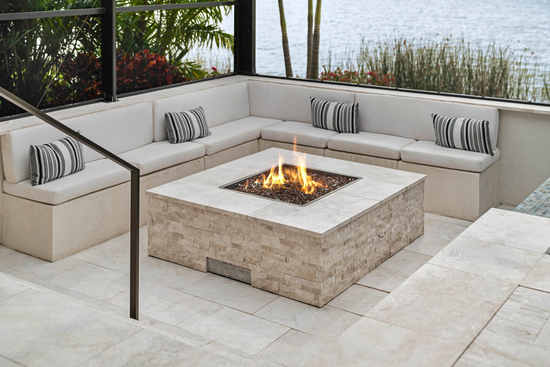 Fire bowl feature at night adjacent to pool, amber flame against dark water