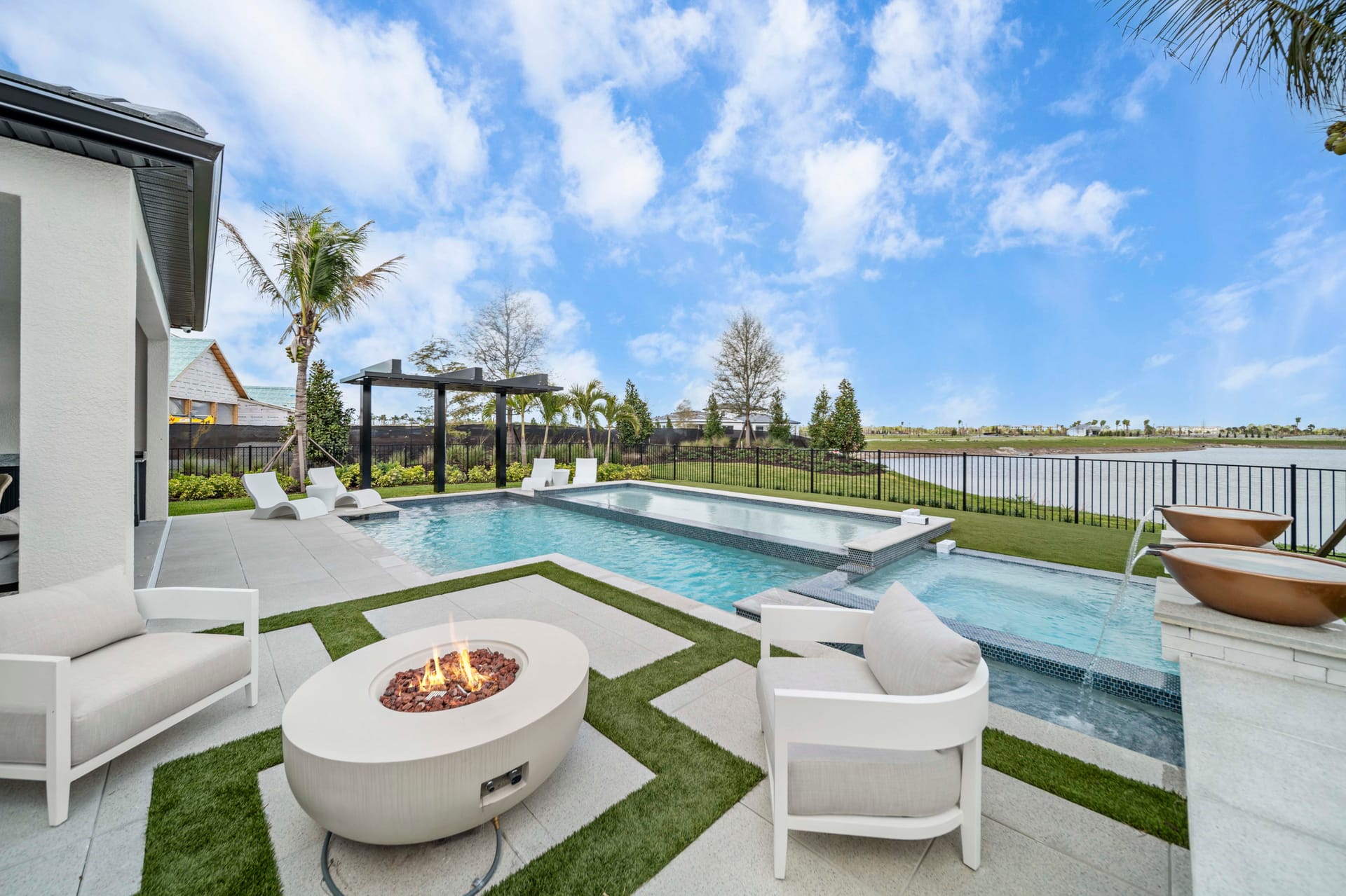Fire bowl feature at night adjacent to renovated pool, amber flame against dark water
