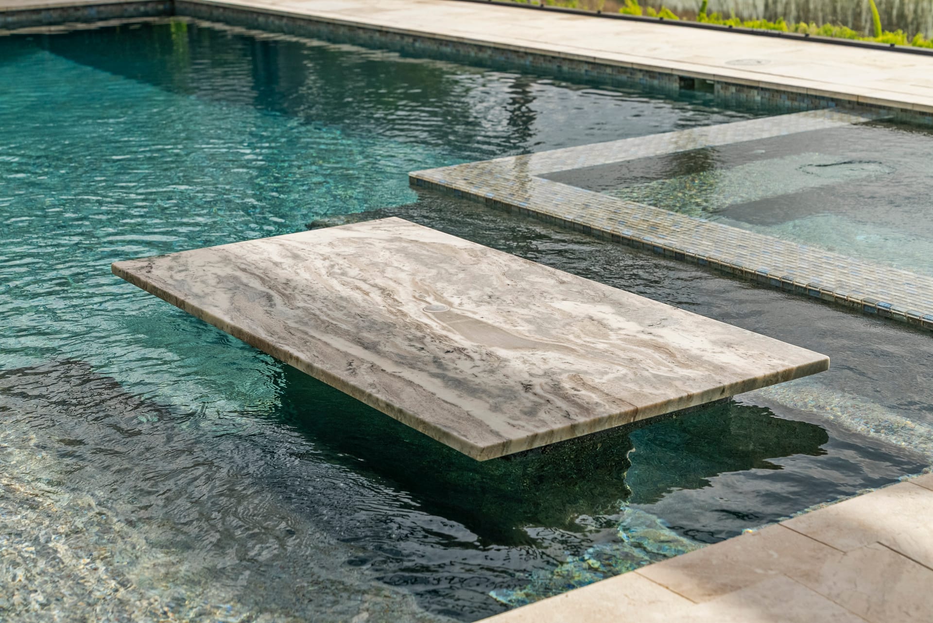 Spillover spa addition integrated with existing pool, evening shot with warm LED lighting